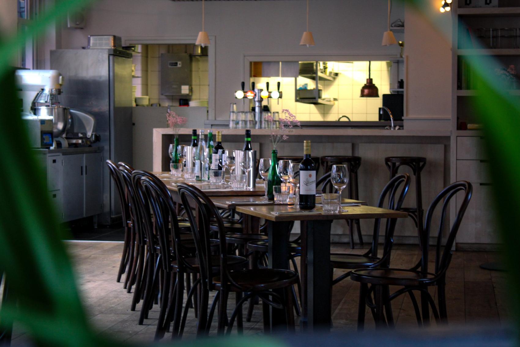 De lange tafel in het eetcafé, gedekt met wijn en glazen